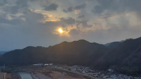 山合いに沈む夕陽と集落