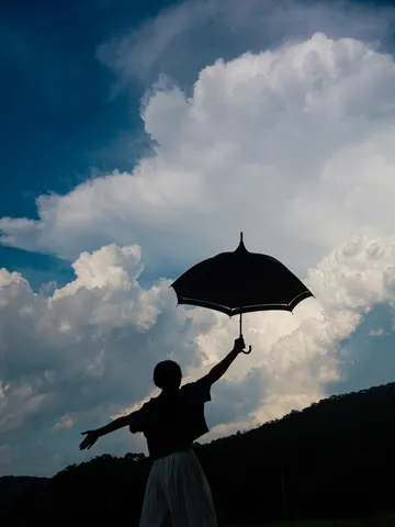 雲をつつく傘とシルエット