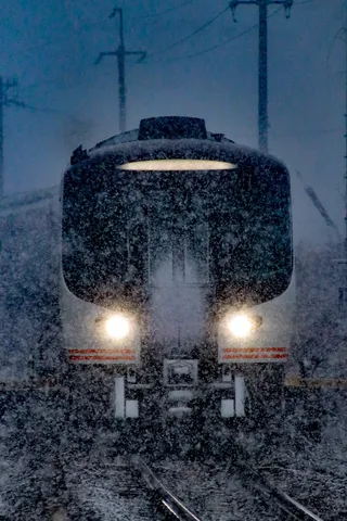 吹雪の中を走る電車のヘッドライト