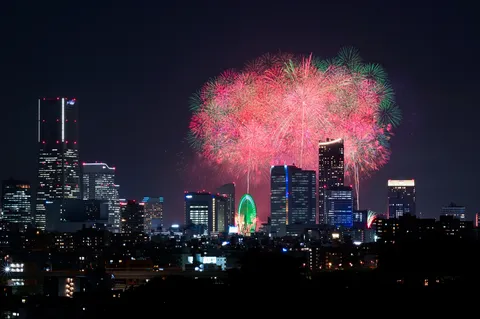 都市の煌めきと花火の競演
