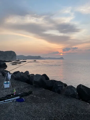 岩と海と釣り竿と夕暮れ