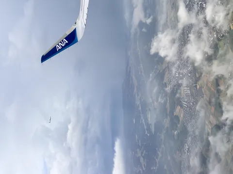 ANAの翼、雲間に小さな飛行機