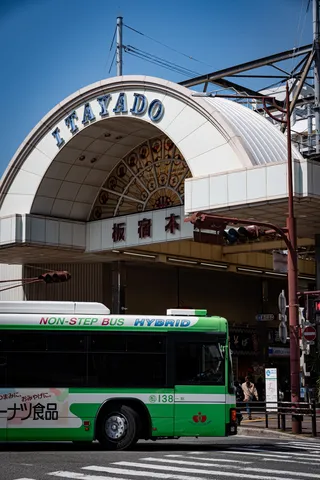 街角のアーチと緑のバス