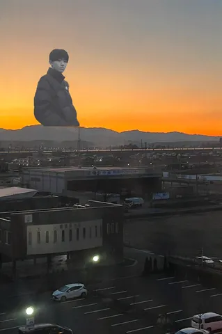 夕焼け空にそびえる巨大な少年