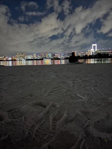 夜の砂浜と光る街景