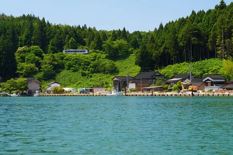 静かな湾岸と緑の丘、そして列車