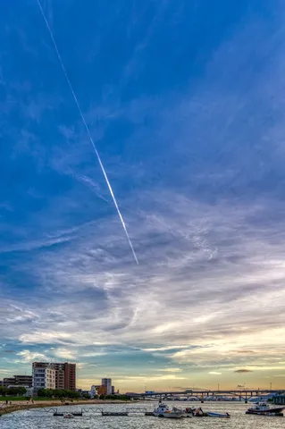 空に伸びる飛行機雲、都会の静けさ