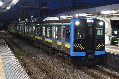 夜のホーム、鮮やかな帯の車両