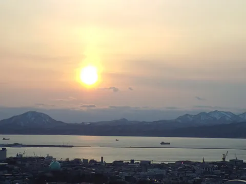静寂な港湾と雪化粧の山々、夕陽のグラデーション