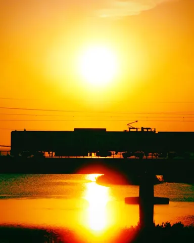 夕陽に染まる列車と水面の光跡