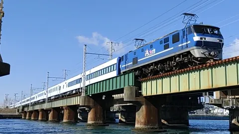 青い機関車と白い列車、橋を渡る。