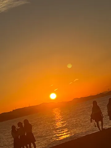 夕暮れ時の海辺、シルエットの少女たち