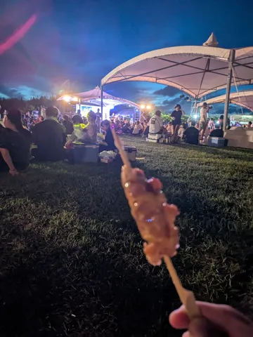 賑やかな夜の会場で、片手に串