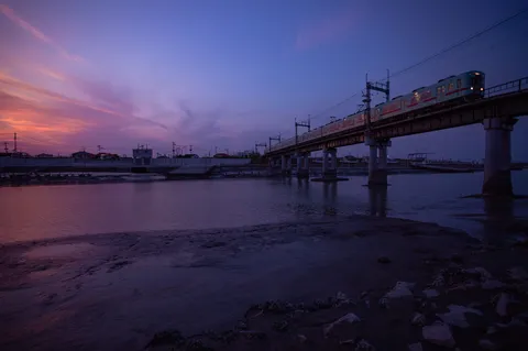 夕暮れの鉄路、水面に映る光