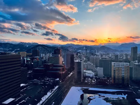 夕景に染まる都市と雪山