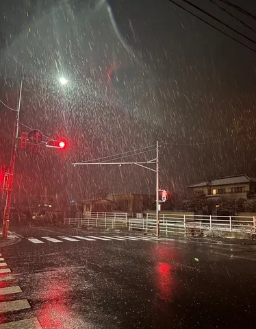雪降る夜の交差点、赤信号の灯り