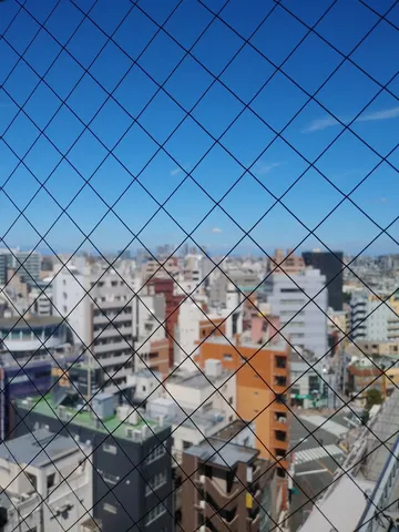 網越しの都会の空
