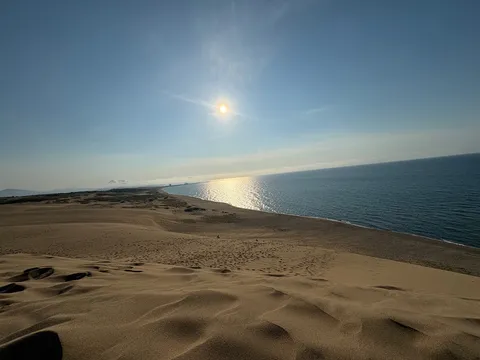 果てなき砂丘と海、太陽の光景