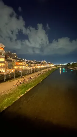 夜の川沿いに灯る人影
