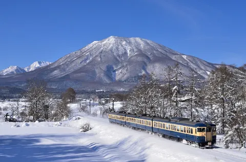 冬の山を駆け抜ける青い列車