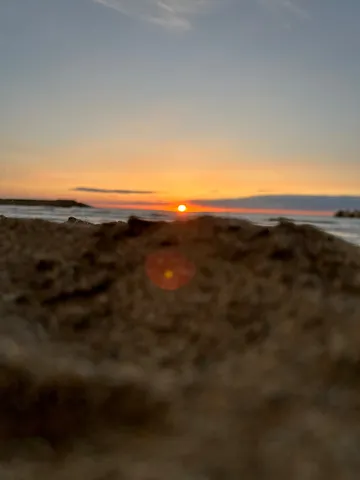 波打ち際、砂粒と夕日