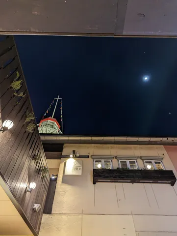 夜空に浮かぶ船と月、灯りのコントラスト