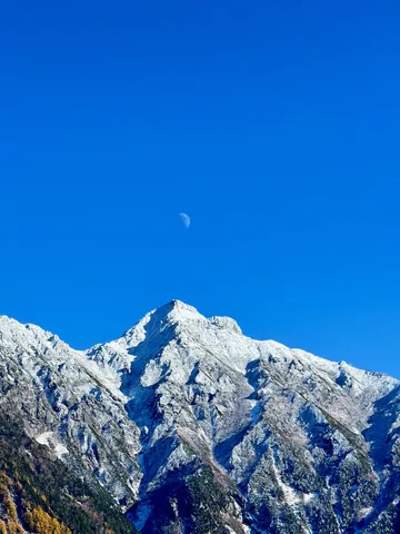秋晴れの峰に佇む月