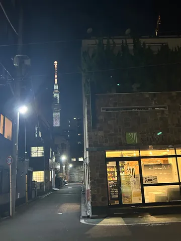 夜の路地に浮かぶ塔の灯り