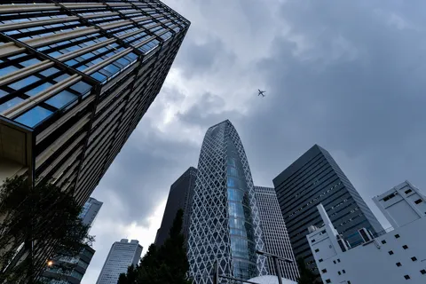 空を見上げる摩天楼と飛行機雲