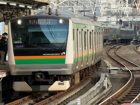 朝のホームに走る緑の列車