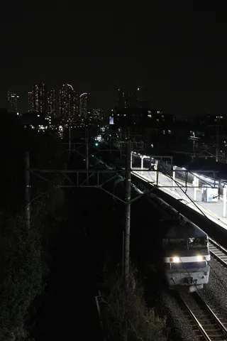 都会のビル街を後にする貨物列車