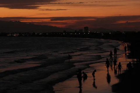 夕暮れの海辺、シルエットの家族たち