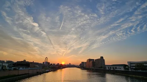 空に広がる飛行機雲と街の灯り