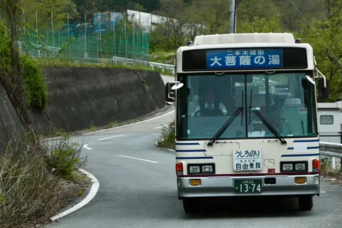 湯へと誘う山道のバス