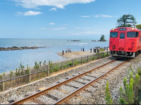 海辺の赤い列車と人影