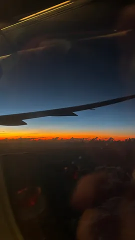 飛行機窓から見た、息をのむような地平線の夕焼け