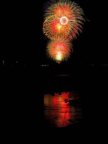 夜空に咲く光の花、水面に映る幻想