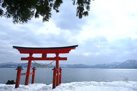 雪降る湖畔の赤い鳥居