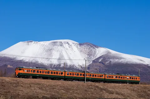 雪山を背に走るレトロな列車
