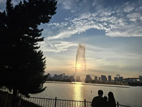 夕暮れ、水辺の噴水と都会のシルエット