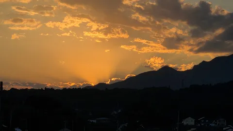太陽のカーテン、山々がシルエットに