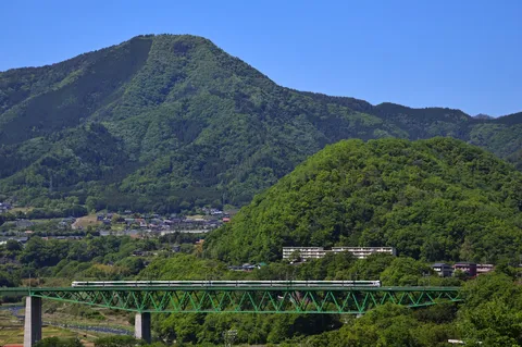 緑深まる山の谷間を駆け抜ける緑の列車