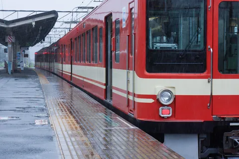 雨の駅に伸びる赤い列車