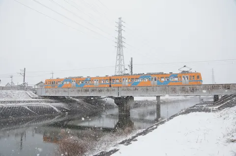 雪景色の鉄路を駆けるオレンジ色の列車