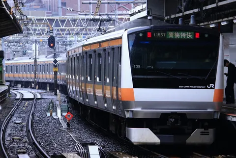 雨のホーム、発車を待つ特快列車