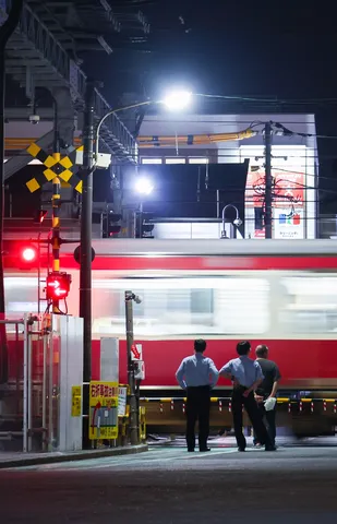 夜の踏切、見守る三人の視線