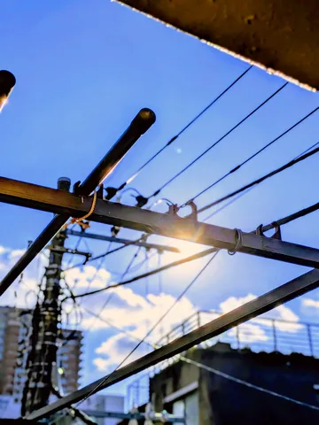 藍空に絡まる電線、光の粒