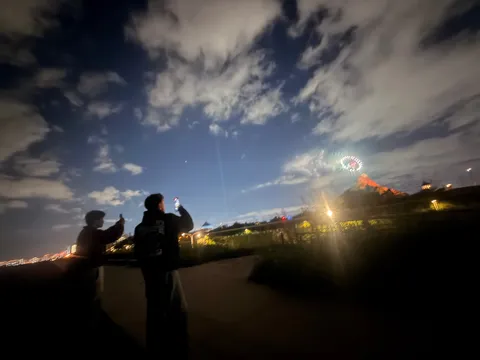 夜空に咲く花火とスマホを構える二人