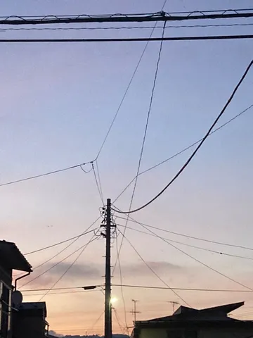 夕暮れ、電線の絡まる空