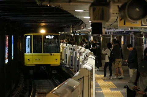 黄の車体と待つ人々